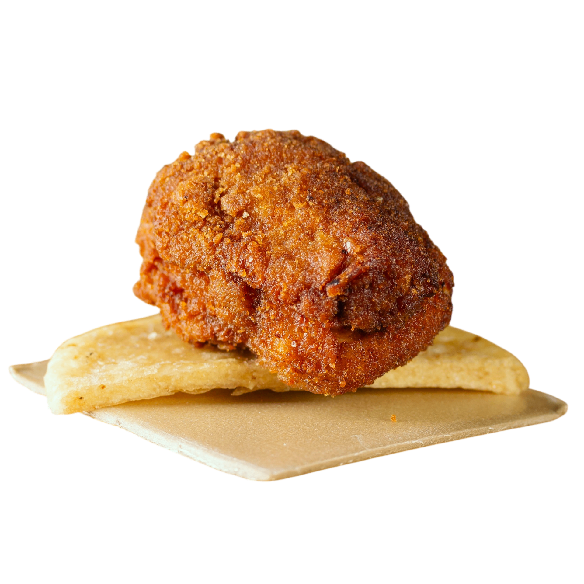 Bombón de pollo apanado en primer plano sobre arepa artesanal